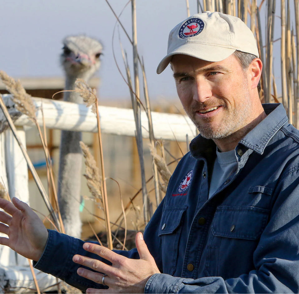 american ostrich farms CEO talking next to an ostrich