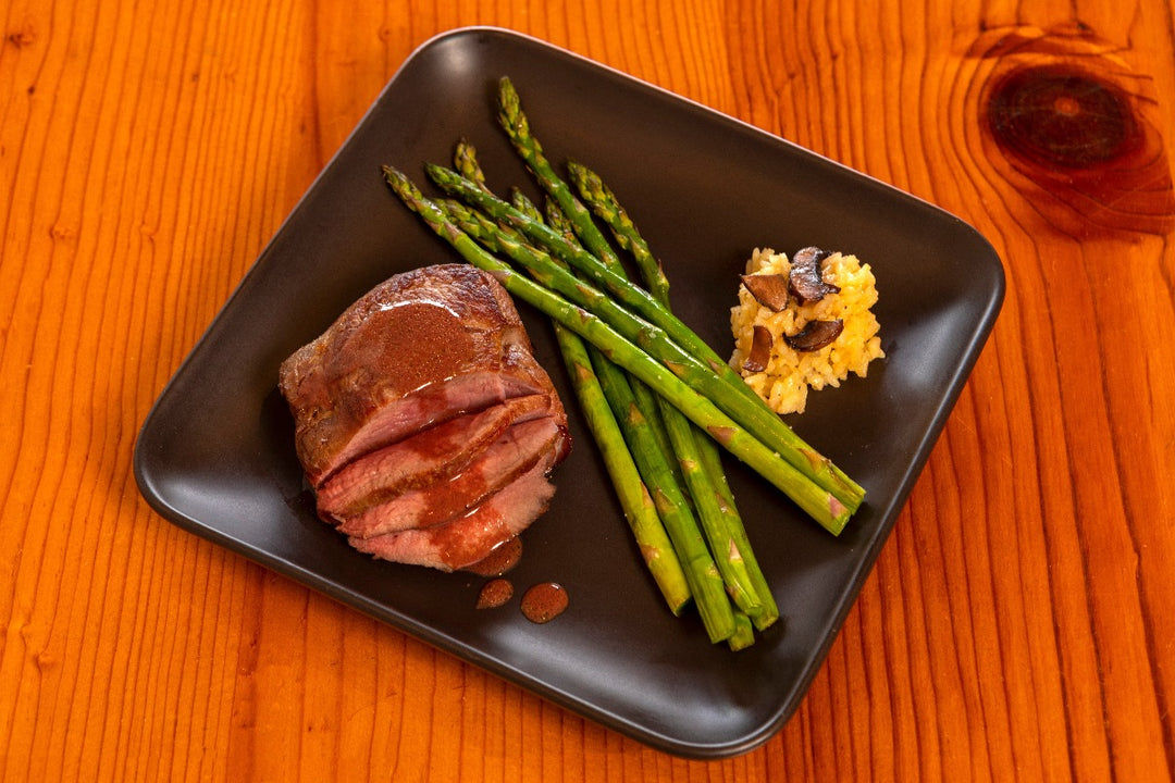 cooked ostrich fan filet with sauce and asparagus