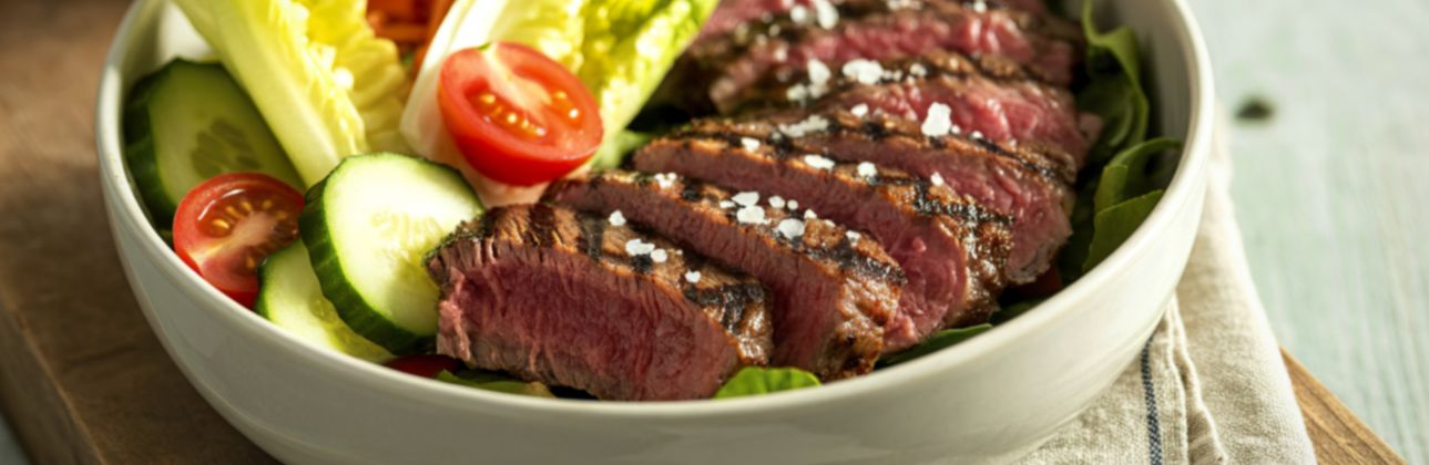 sliced ostrich steak on a bed of lettuce and vegetables