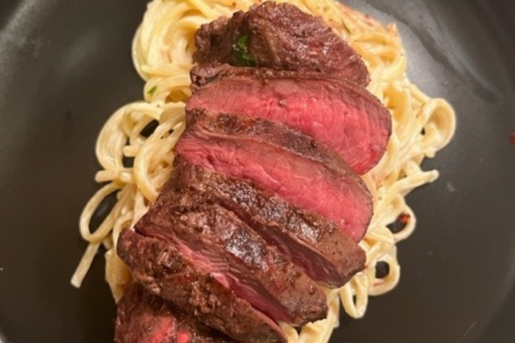 Ostrich steak on top of pasta