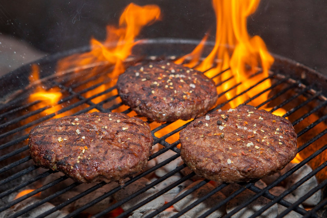 3 ground ostrich steak burgers being flame grilled