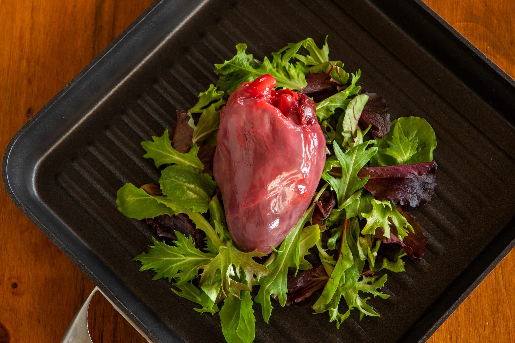 raw ostrich heart on bed of greens