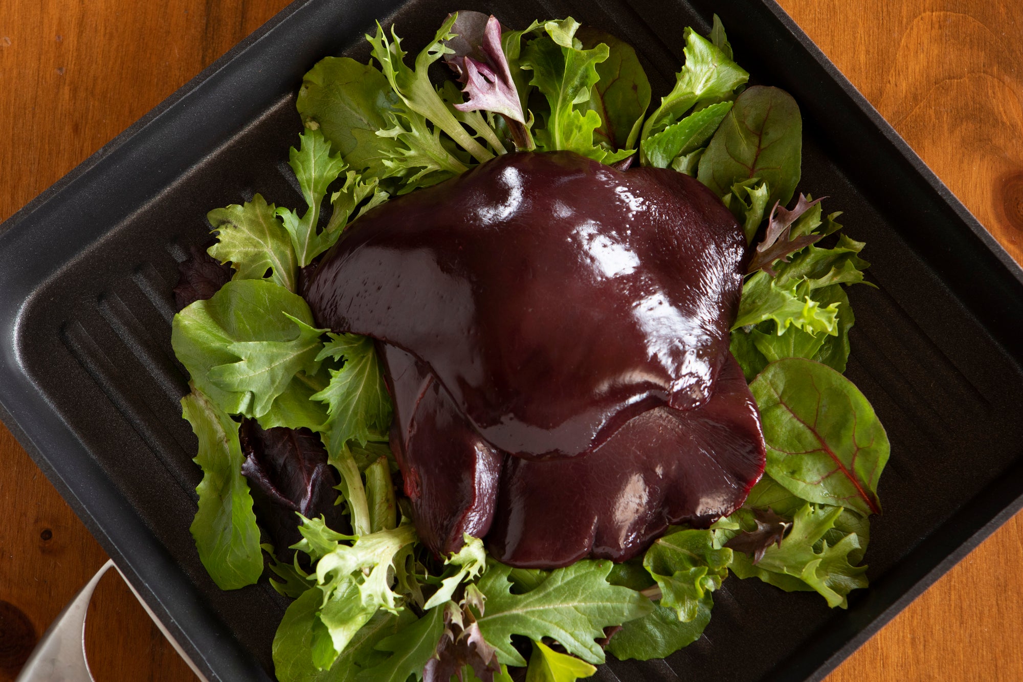 raw ostrich liver on bed of greens