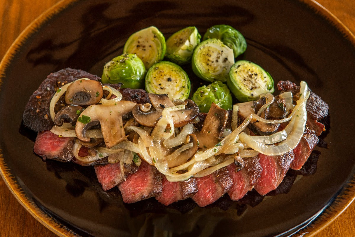 cooked and sliced ostrich tenderloin with onions and mushrooms