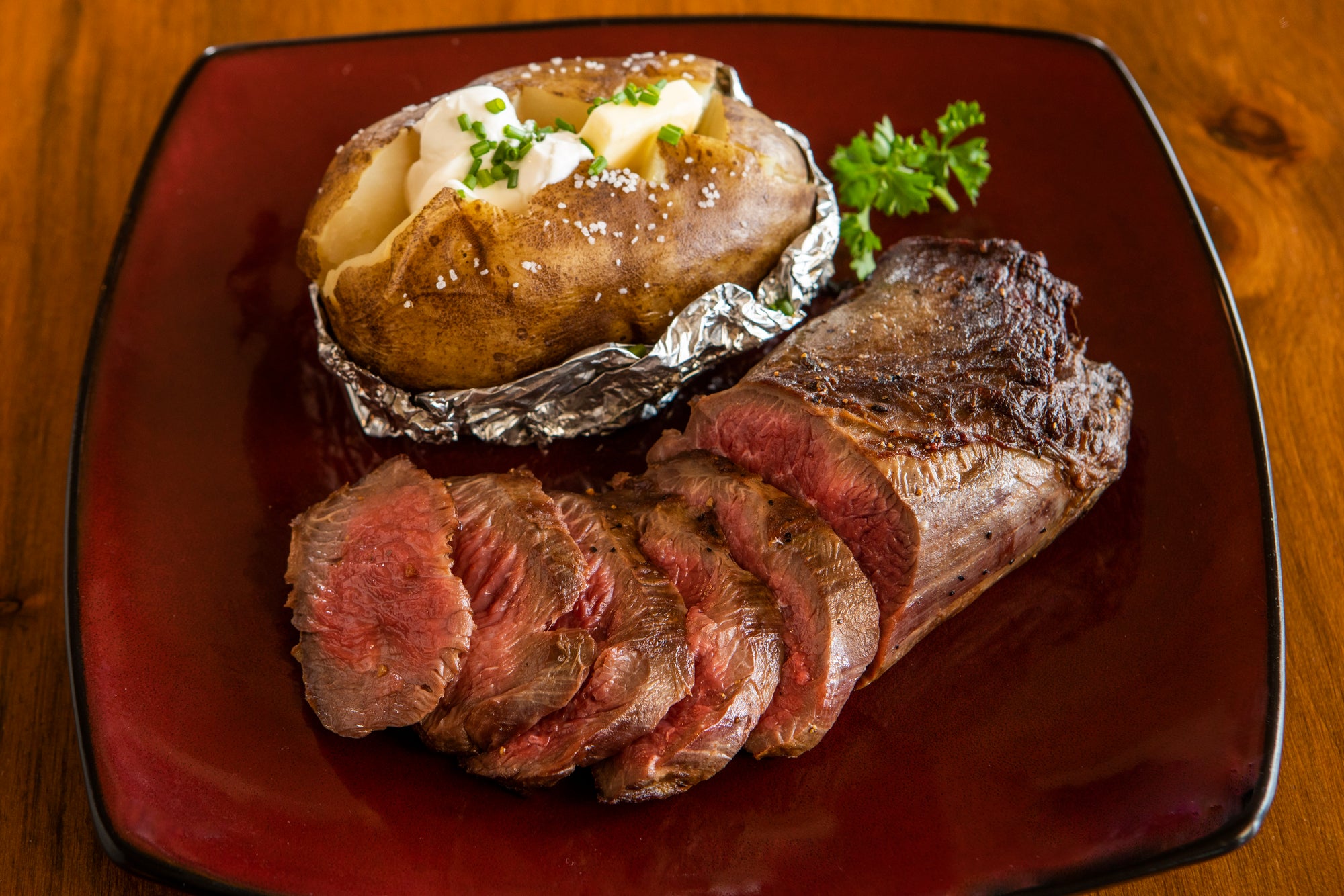 cooked and sliced ostrich top loin with baked potato