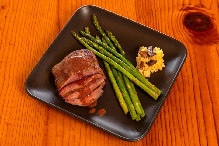 cooked ostrich fan filet with sauce and asparagus 